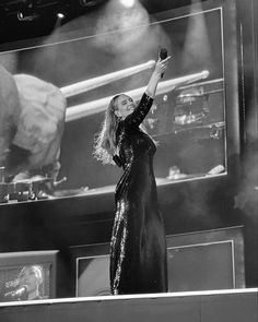 a black and white photo of a woman on stage with her arms in the air