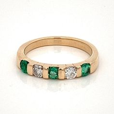 an emerald and diamond ring on a white surface