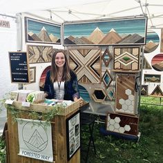 a woman is standing behind a booth selling art