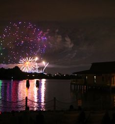 fireworks are lit up in the night sky over water