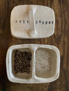 salt and pepper in white dishes with words on them sitting on a wooden table next to each other