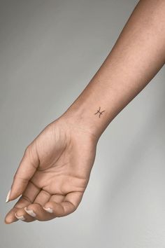 a woman's arm with a small airplane tattoo on the left side of her wrist