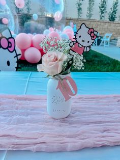 a hello kitty themed party with pink and white flowers in a mason jar filled with baby's breath