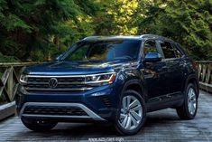 a blue volkswagen suv is parked on a bridge in front of some trees and bushes