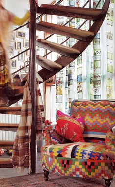 a living room filled with furniture and a spiral staircase in front of a painting on the wall