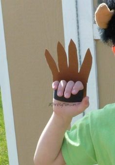 a young boy holding up a fake hand made out of brown paper with horns on it