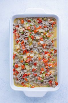 a casserole dish with meat and vegetables in it on a white table top