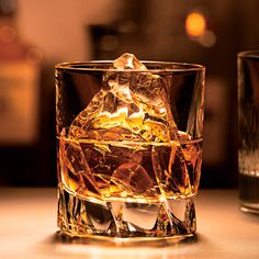 an ice cube sitting on top of a table next to a glass filled with liquid