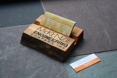 a wooden business card holder sitting on top of a stone floor next to a tag