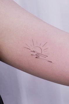 a woman's arm with a small sun tattoo on the left side of her arm