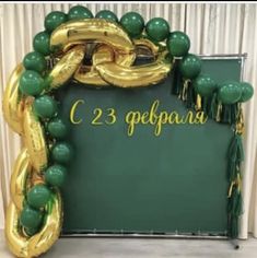 the balloon arch is decorated with green and gold balloons