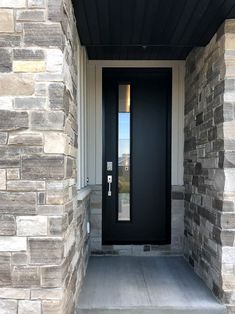 a black front door on a house with stone pillars and sidelights in the window