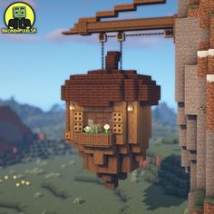 an animated image of a wooden house hanging from a beam in the sky with mountains and trees behind it