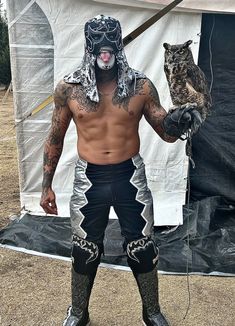 a man in an animal mask and leggings stands next to a white tent