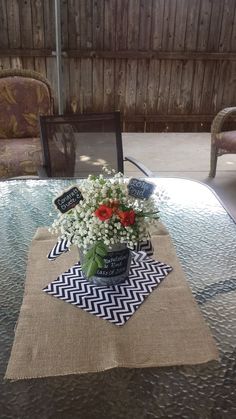 a table topped with a vase filled with flowers on top of a cloth covered table