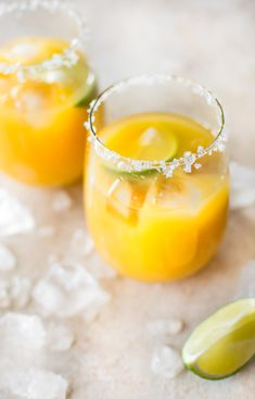 two glasses filled with orange juice and garnished with lime