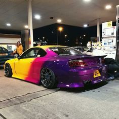 a purple and yellow car parked at a gas station