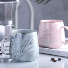 two marbled coffee mugs sitting next to each other on a white countertop