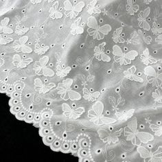 white lace with butterflies on it is laying on a black tablecloth, close up