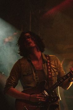 a man with long hair playing an electric guitar