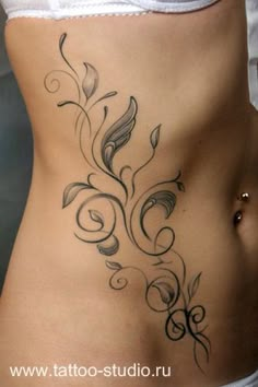 a woman's stomach with an artistic tattoo design on the side, and leaves