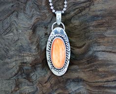 One of a kind Orange Spiny Oyster Sterling Silver Pendant on a diamond cut bead chain with a lobster clasp. The setting is an oval spiny oyster cabochon that is 20mm x 10mm and in a bezel setting accented with twisted wire. The 925 Sterling Silver chain is 18". Add a pop of color and glamour to your boho chic jewelry collection with this fabulous necklace. Perfect for spiny oyster lovers and those who appreciate the beauty of natural gemstones and artisan craftsmanship. The oyster shell is about Oyster Shell Pendant, Spiny Oyster Necklace, Luxury Orange Sterling Silver Necklace, Spiny Oyster Jewelry Native American, Oyster Necklace, Sterling Silver Gemstone Necklace, Spiny Oyster Jewelry, Necklace Chunky, Twisted Wire