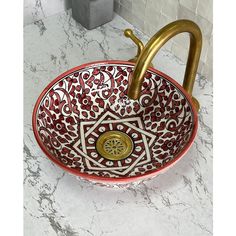 a red and white bowl sink sitting on top of a counter next to a faucet