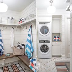 a washer and dryer in a white laundry room with striped towels on the shelves