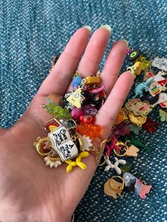 a person's hand is full of charms and keychains on a blue blanket