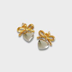 For all those bow and heart lovers! Bow stud with silver puff heart charm. 18k gold plated stainless steel Silver heart charm Diameter: 20 x 22mm Tarnish and sweat resistant Hypoallergenic no green skin 1 year warranty Gold Plated Silver Heart Earrings For Anniversary, Silver Gold-plated Heart Earrings, Cute Gold Heart Earrings For Gift, Silver Gold-plated Heart Earrings For Gifts, Silver Gold Plated Heart Earrings Gift, Gift Silver Gold Plated Heart Earrings, Gold Sterling Silver Heart Earrings For Party, Gold Heart Earrings For Party, Green Skin