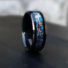 a black ring with blue and gold skulls inlayed to the side on a table