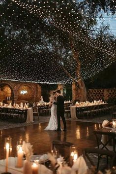 a bride and groom standing in the middle of a dance floor surrounded by lit candles