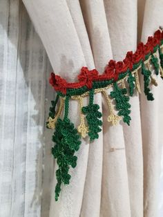 the curtain is decorated with green and red crocheted garlands on it's side