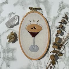 a cross - stitch pattern with a wine glass on it and some dried flowers next to it