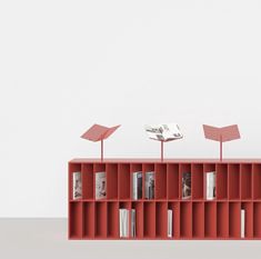 an orange book shelf with three books on top and two small red lamps above it