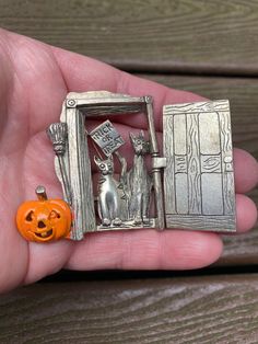 a person holding a small silver charm with an orange pumpkin in it's hand