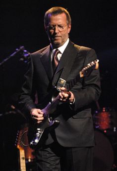 a man in a suit playing an electric guitar