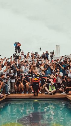 a large group of people sitting on the edge of a pool with cameras around them