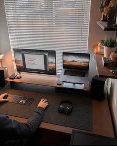 a person sitting at a computer desk with two monitors and a keyboard in front of them