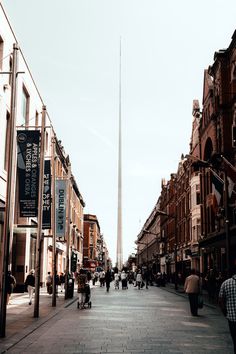 people are walking down the street in front of buildings and a tall obelisk