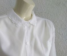 70s does 50s embroidered blouse sheer minimalist blouse ribbon embroidery collar feminine romantic blouse delicate simple elegant blouse Materials: minimalist delicate blouse, ribbon embroidered collar 70s does 50s embroidered blouse, sheer minimalist blouse, ribbon embroidery on collar and on the small chest pocket, feminine romantic blouse, delicate simple elegant blouse, polyester. Made in England. Measurements laying flat : shoulders :44cm (17,5 inches) bust:60 cm (23,5 inches) total lenght Elegant White Shirt With Floral Embroidery, Elegant Floral Embroidered Summer Shirt, Elegant Shirt With Lace Collar For Spring, Elegant Embroidered Summer Shirt, Summer Formal Blouse With Lace Collar, Summer Wedding Top With Collar, Feminine Embroidered Formal Blouse, Elegant Shirt With Peter Pan Collar For Summer, Elegant Summer Blouse With Peter Pan Collar