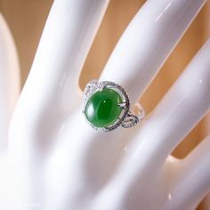 Here is stunning translucent large AAA gem grade oval emerald green nephrite jade diamond ring. The jade is set in a diamond halo setting in solid 18KT white gold. The jade is about 10x12mm and is approx. 5.90 carats. The total weight of the brilliant cut round white diamonds is 0.23 carats. The band is about 2.5mm. This is a significant size ring and it sits high on your finger. This ring would make a statement and is a lovely cocktail ring or engagement ring! Dimensions: Natural untreated AAA Green Emerald Oval Cabochon Ring For Wedding, Green Oval Cabochon Emerald Ring For Wedding, Green Jade Wedding Rings, Jade Rings Oval Cabochon For Anniversary, Oval Jade Ring Fine Jewelry, Oval Jade Ring For Wedding, Fine Jewelry Jade Oval Ring, Oval Jade Rings For Anniversary, Oval Jade Wedding Ring