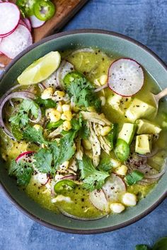 a bowl filled with soup next to sliced radishes and cilantros