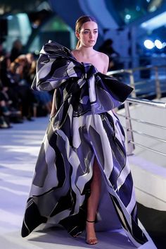 a model walks down the runway in a purple and black dress