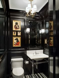 a black and white bathroom with pictures on the wall above the toilet, sink and mirror