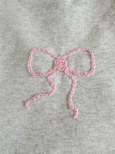 a close up of a sweater with a pink bow on the front and back of it