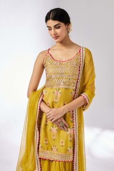 Discover timeless elegance with this exquisite set featuring a cotton silk kurta with strappy detailing and artistic design. Paired with a graceful georgette sharara for a chic, flowing silhouette, and a sheer chiffon dupatta for an ethereal finish. Embrace a blend of classic romance and modern style for any special occasion. Yellow Georgette Sharara With Straight Kurta, Anarkali Sharara With Traditional Drape For Summer, Silk Sharara With Zari Work For Summer, Summer Sharara With Dori Work, Summer Anarkali Sharara In Georgette, Festive Yellow Cotton Silk Palazzo Set, Silk Sharara For Summer, Silk Sharara With Straight Kurta For Summer, Summer Chanderi Sharara With Resham Embroidery