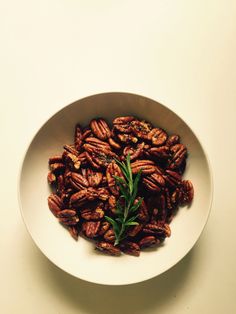 a white bowl filled with pecans on top of a table