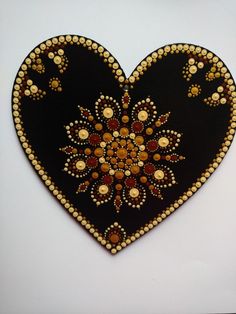 a black heart with gold and red designs on it's sides is hanging from the wall