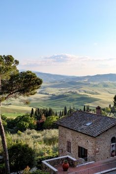 an old stone house in the countryside with rolling hills and valleys behind it, as seen from above